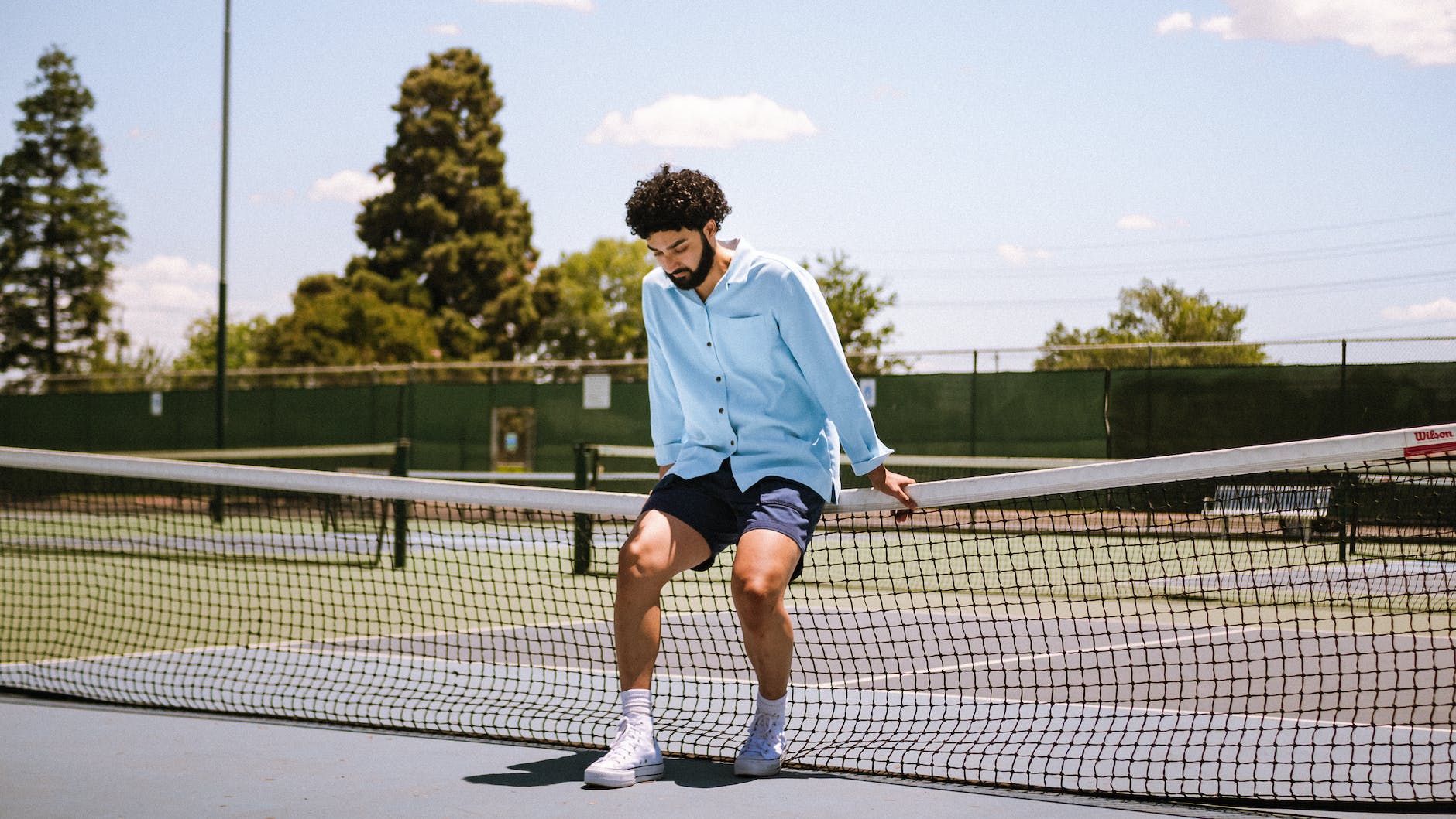 man sitting on tenis court net